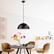 Schwarze, halbkugelförmige Pendelleuchte mit langem Kabel über einem Esstisch in modernem Esszimmer, frontale Innenraumaufnahme mit leichtem Blick von unten auf die Lampe