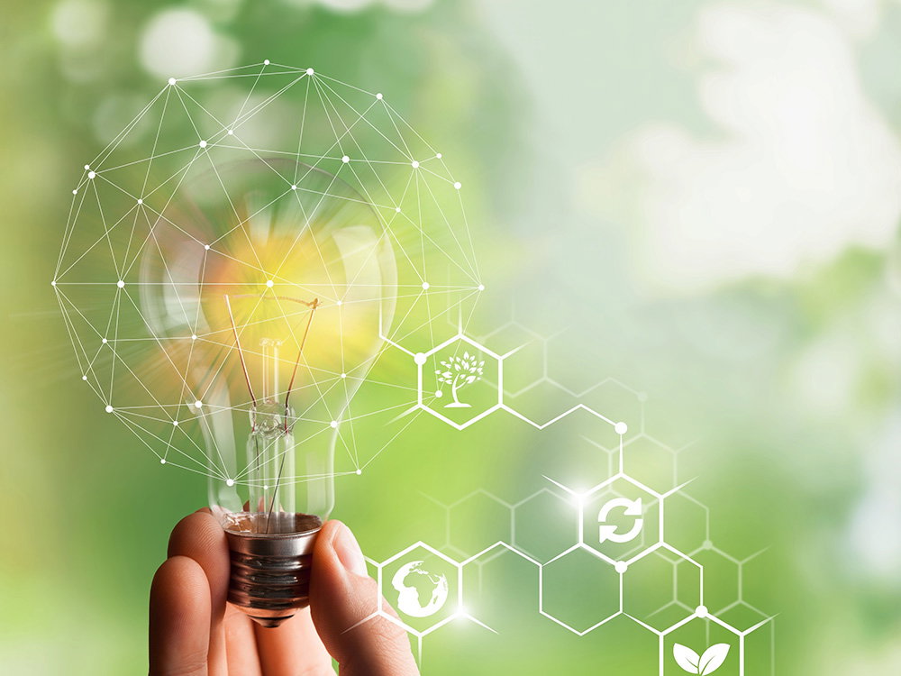Hand hält leuchtende Glühbirne mit Symbolen für erneuerbare Energie und nachhaltige Innovation