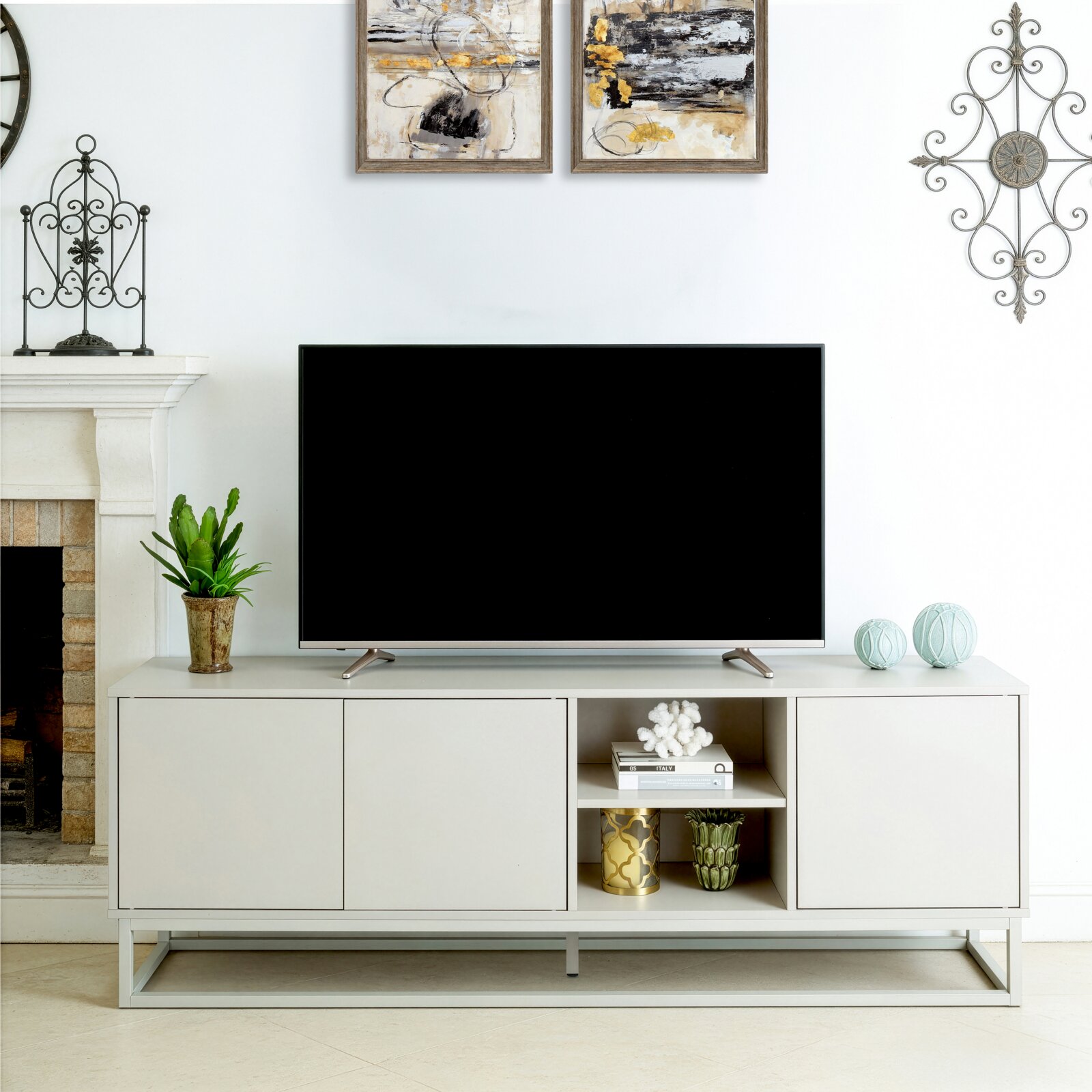 XORA TV-Lowboard RUBY Modernes weißes TV-Lowboard mit großem Flachbildfernseher und offenen Regalfächern, frontal aus Augenhöhe fotografiert, dekoriert mit Pflanze, Büchern und Vasen vor heller Wohnzimmerwand.
