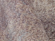 Nahaufnahme eines Designer-Teppichs mit melierter Textur in Beige- und Grautönen, seitliche Perspektive