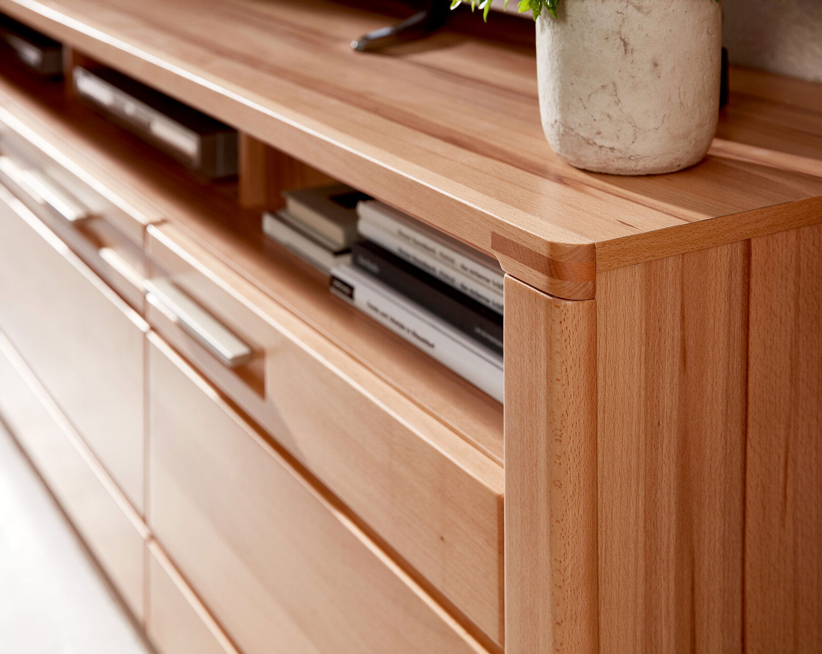 Nahaufnahme eines TV-Lowboards aus Holz mit modernen Griffen und offenen Fächern, seitliche Perspektive