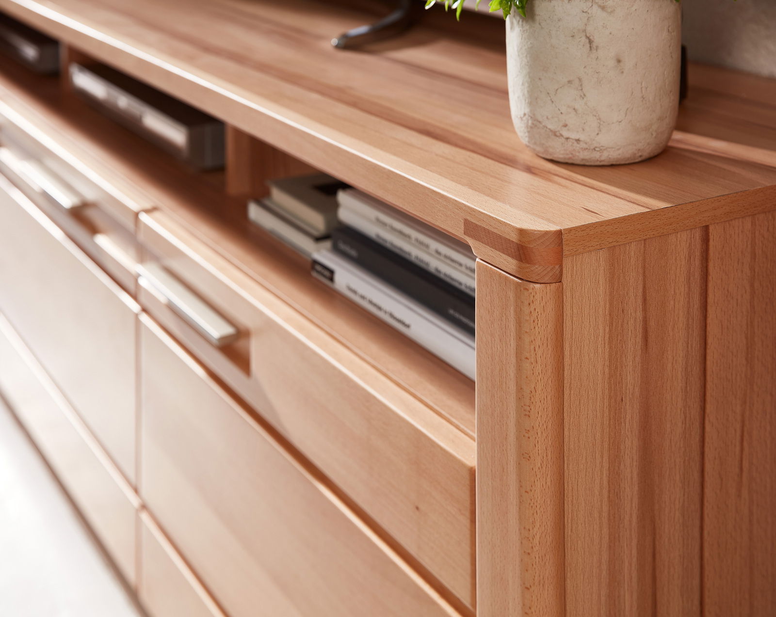 Nahaufnahme eines TV-Lowboards aus Holz mit modernen Griffen und offenen Fächern, seitliche Perspektive