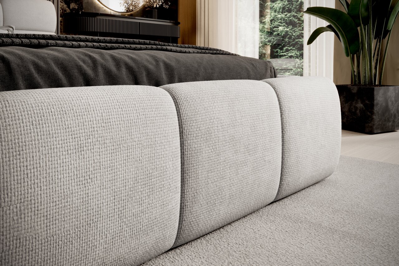 Nahaufnahme eines Polsterbettgestells in hellem Stoff, seitliche Perspektive.