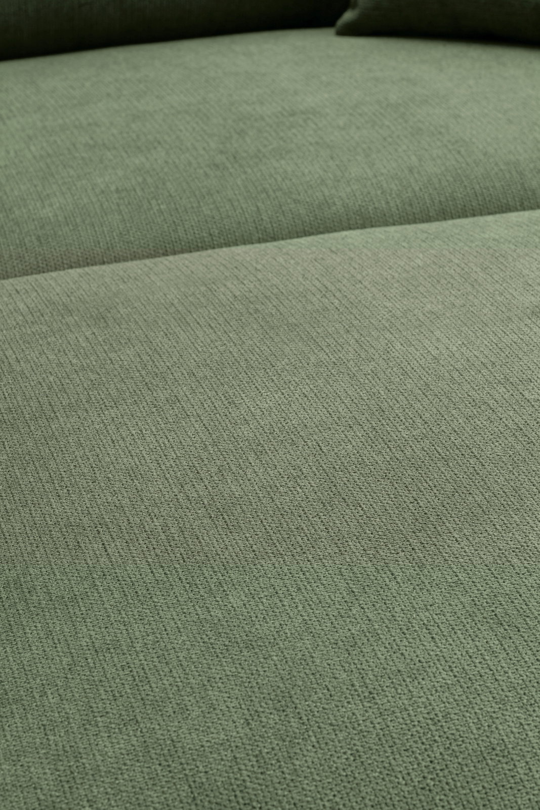 Nahaufnahme einer grünen Stoffoberfläche eines Sofas aus der Vogelperspektive.