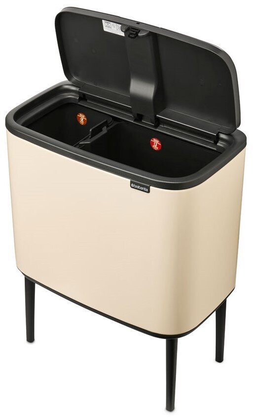 Brabantia Abfalleimer BO Beigefarbener Abfalleimer mit zwei Fächern, geöffnet, auf schwarzen Beinen, aus schräger Perspektive.