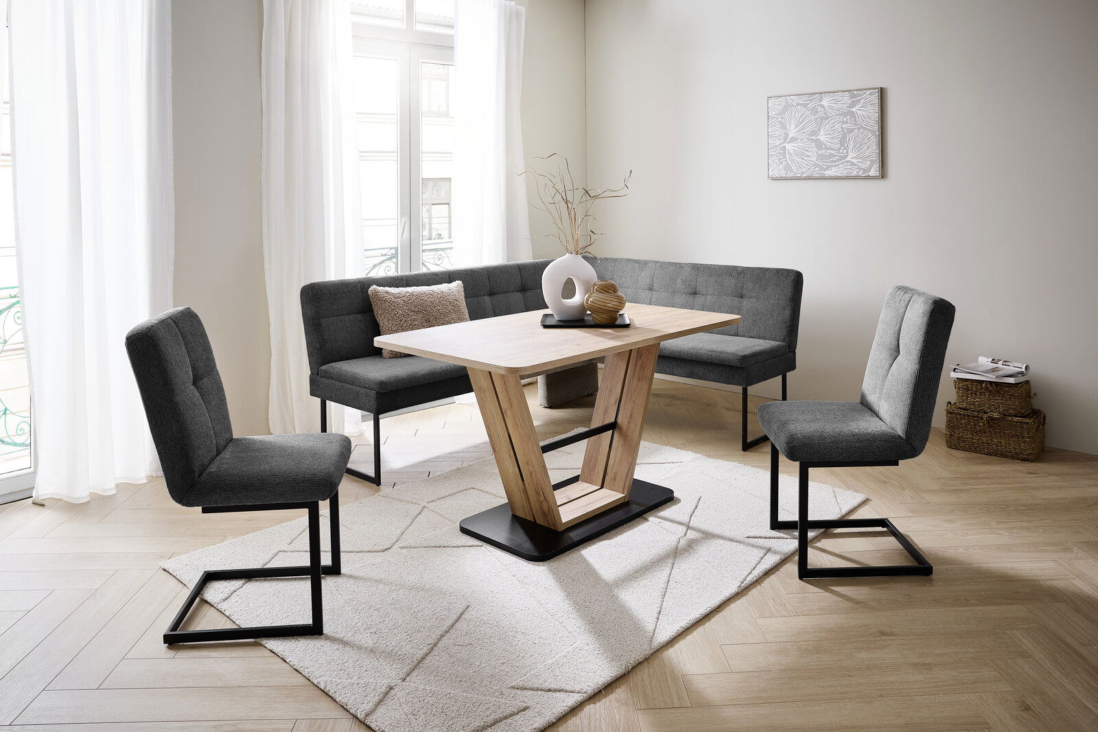 Moderne Esszimmer-Eckbankgruppe mit grauen Polstern und Holztisch in einem hellen Raum, seitliche Perspektive.