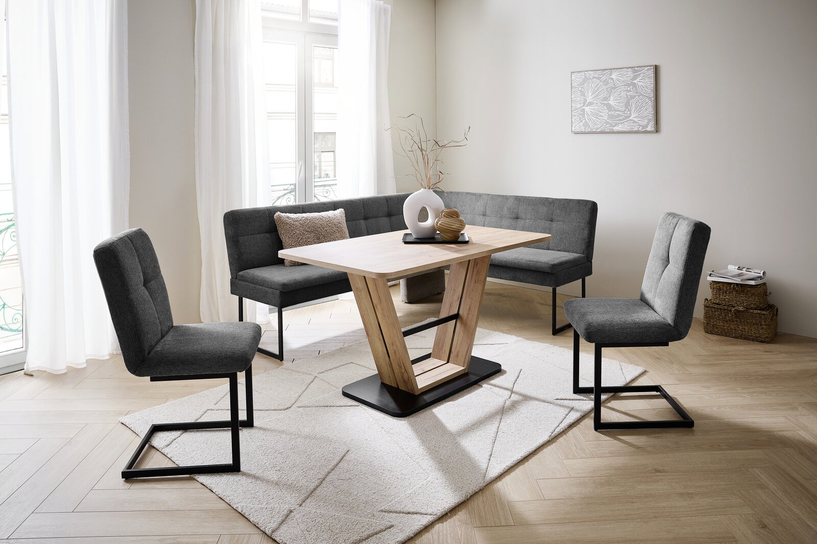 Moderne Esszimmer-Eckbankgruppe mit grauen Polstern und Holztisch in einem hellen Raum, seitliche Perspektive.