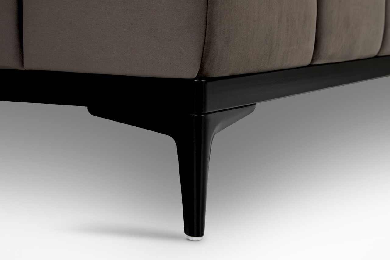 Nahaufnahme eines schwarzen Sofafußes mit grauem Stoffbezug, seitliche Perspektive