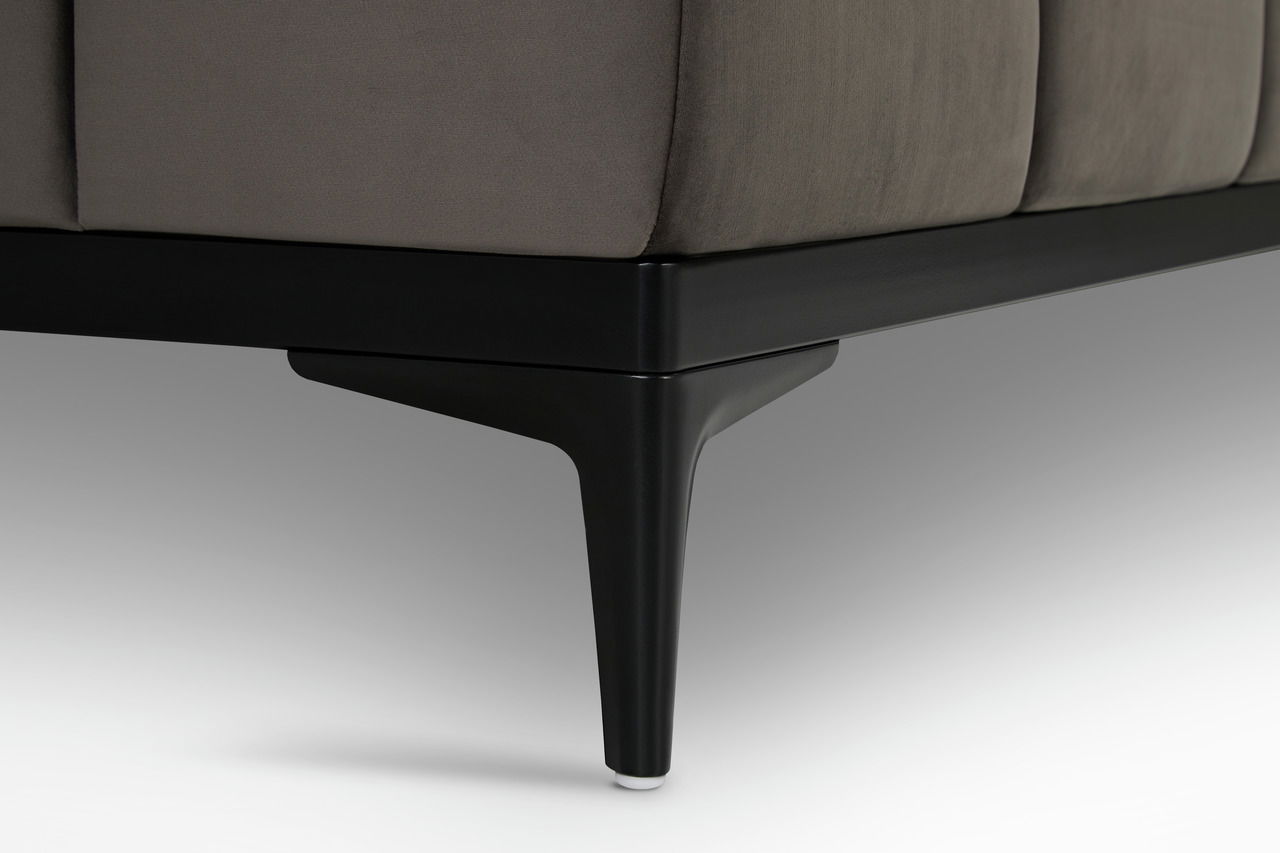 Nahaufnahme eines schwarzen Sofafußes mit grauem Stoffbezug, seitliche Perspektive