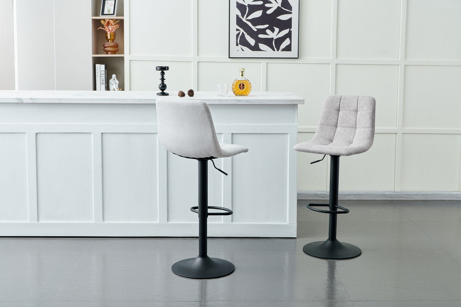 Zwei moderne Barhocker mit gepolsterten Sitzen und schwarzem Metallfuß, vor einer weißen Theke in einem stilvollen Raum, seitliche Perspektive.