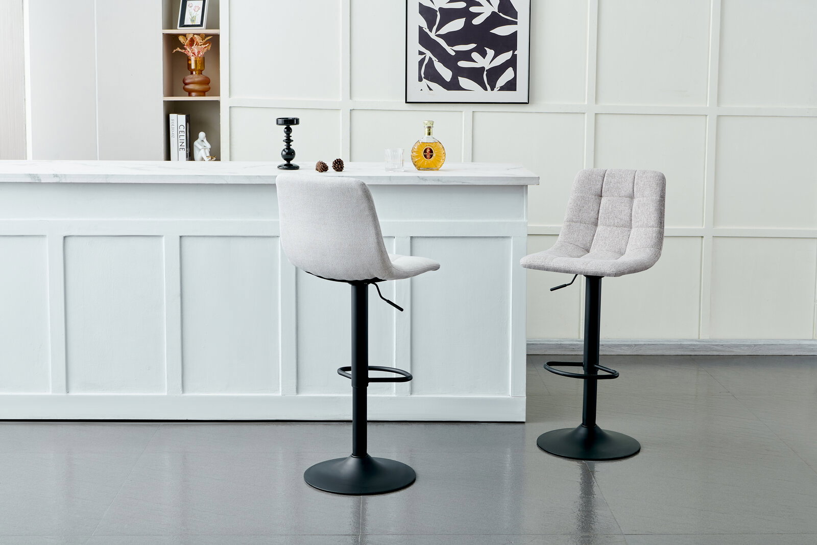 Zwei moderne Barhocker mit gepolsterten Sitzen und schwarzem Metallfuß, vor einer weißen Theke in einem stilvollen Raum, seitliche Perspektive.