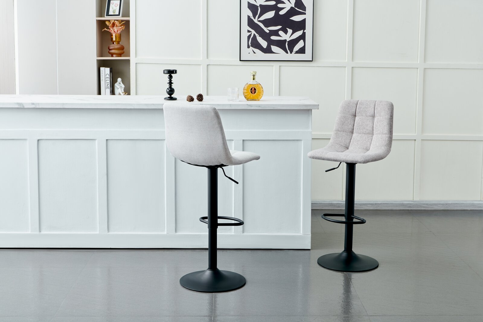 Twee moderne barkrukken met gestoffeerde zittingen en een zwart metalen onderstel, voor een witte bar in een stijlvolle ruimte, gezien vanuit de zijkant.