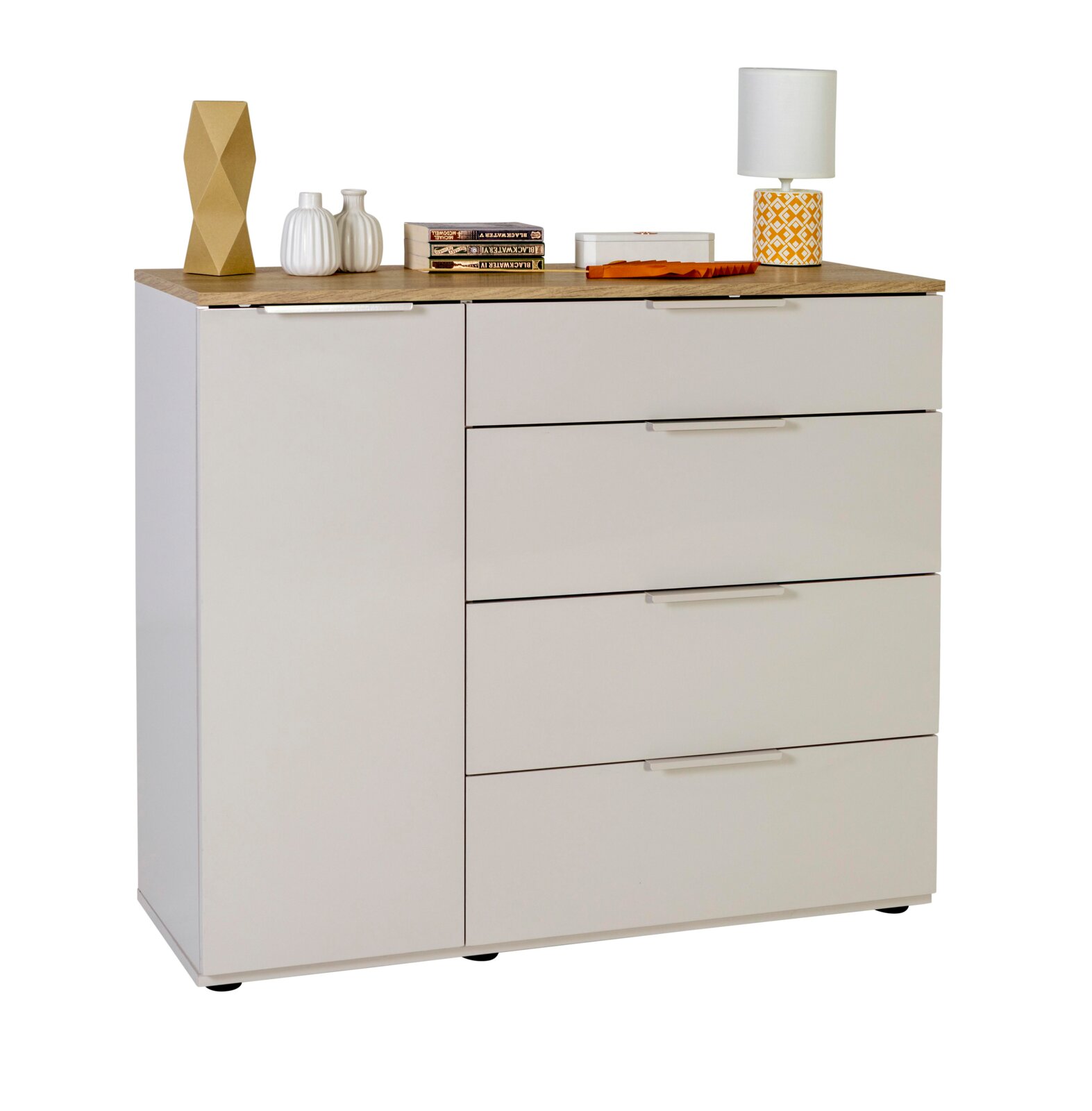 Weiße Kommode mit Holzoptik-Oberplatte, links eine Tür und rechts vier Schubladen mit Griffleisten; dekoriert mit Vasen, Büchern und Tischlampe, Frontansicht leicht von links.