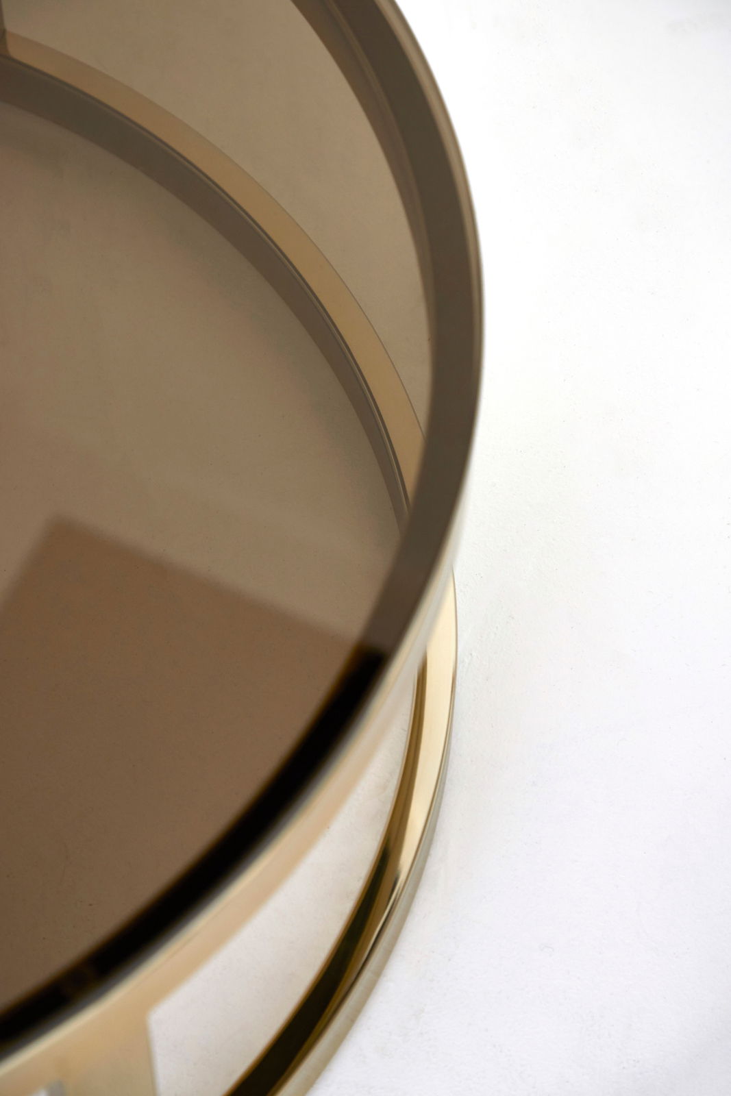 Nahaufnahme eines runden Couchtisches mit einer Glasplatte und einem goldenen Rahmen, von oben betrachtet.