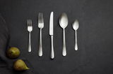 Besteckset aus Edelstahl mit gehämmertem Griff, bestehend aus Gabel, Messer, Löffel und Teelöffel, auf dunklem Hintergrund von oben fotografiert.
