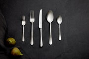 Besteckset aus Edelstahl mit gehämmertem Griff, bestehend aus Gabel, Messer, Löffel und Teelöffel, auf dunklem Hintergrund von oben fotografiert.