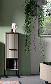 Moderner Standschrank mit vertikalen Streifen, dekoriert mit einer Skulptur und Kerzen auf der Oberseite, in einem Raum mit hängenden Pflanzen. Frontalansicht.