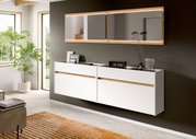 Modernes, schwebend montiertes Sideboard in Weiß mit Holz-Akzentfuge unter einem breiten Wandspiegel mit Holzrahmen; Szene in leichter Schrägansicht von vorn.