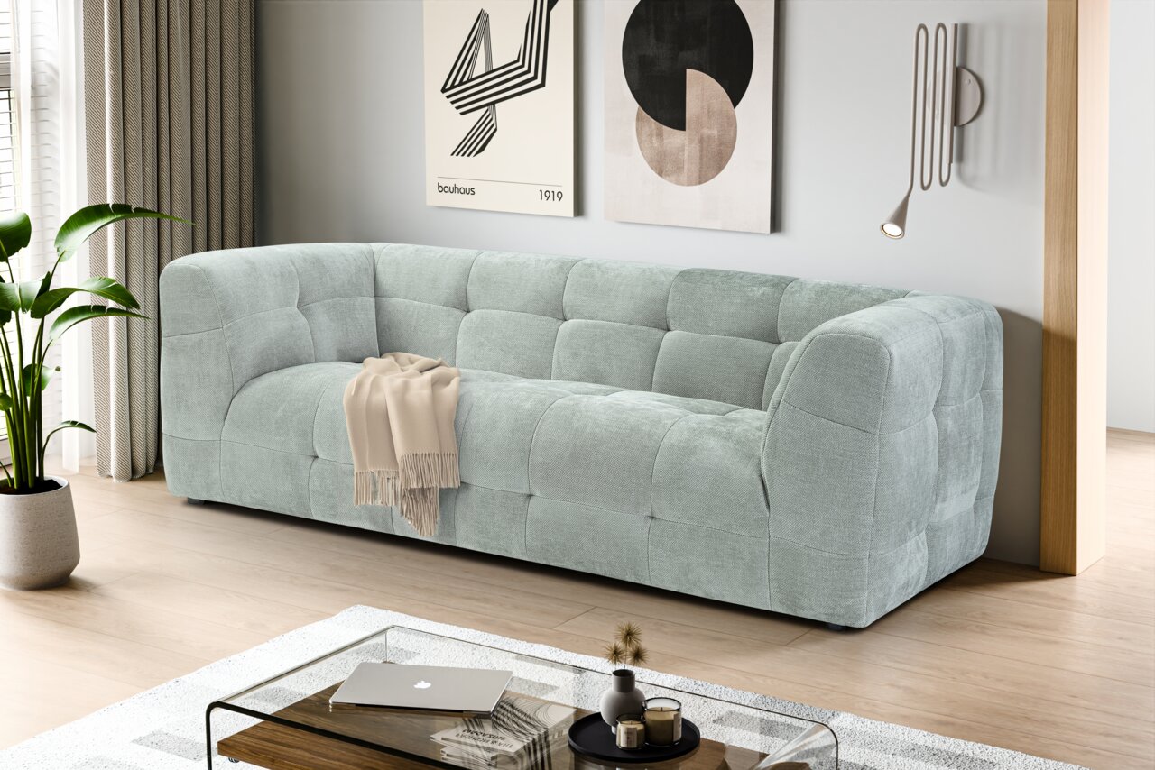 MID.YOU Sofa 2,5 Sitzer TENSO Modernes, hellgraues Stoffsofa mit gepolsterter Kassetten-Steppung in einem minimalistischen Wohnzimmer, schräg von vorne aus leicht erhöhter Perspektive fotografiert