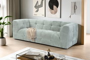 Modernes, hellgraues Stoffsofa mit gepolsterter Kassetten-Steppung in einem minimalistischen Wohnzimmer, schräg von vorne aus leicht erhöhter Perspektive fotografiert