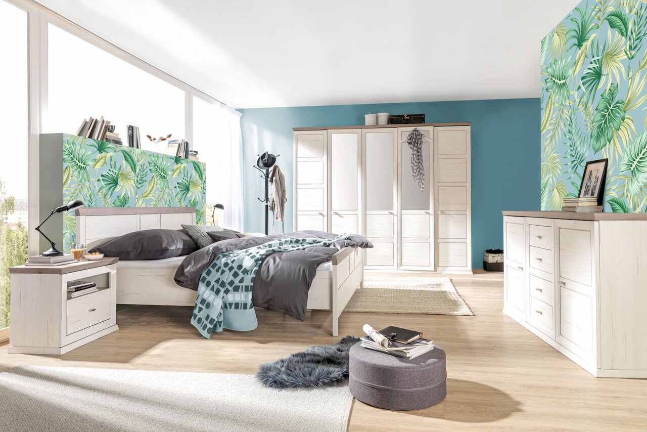 Hom´in Sideboard CAMRON Helles Schlafzimmer mit einem 5-türigen Drehtürenschrank, einem großen Bett, einer Nachtkommode und einem Sideboard in Holzoptik. Die Perspektive zeigt den Raum von der Seite mit Blick auf das Bett und den Schrank.