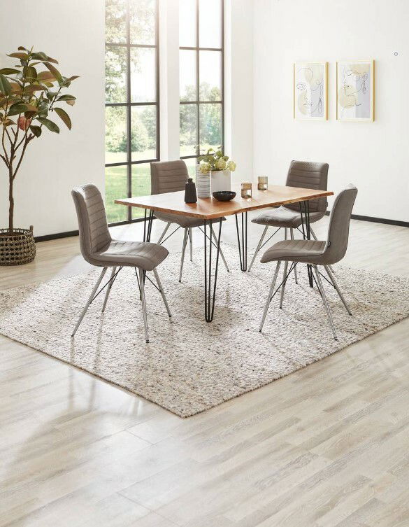 Moderner Esstisch mit Holzplatte und Metallbeinen, umgeben von vier grauen Stühlen auf einem Teppich, in einem hellen Raum mit großen Fenstern, seitliche Perspektive.