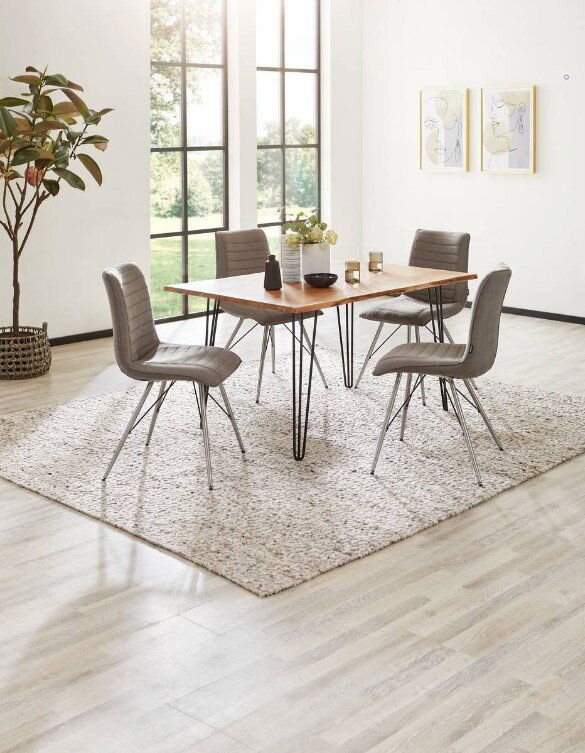 Moderner Esstisch mit Holzplatte und Metallbeinen, umgeben von vier grauen Stühlen auf einem Teppich, in einem hellen Raum mit großen Fenstern, seitliche Perspektive.