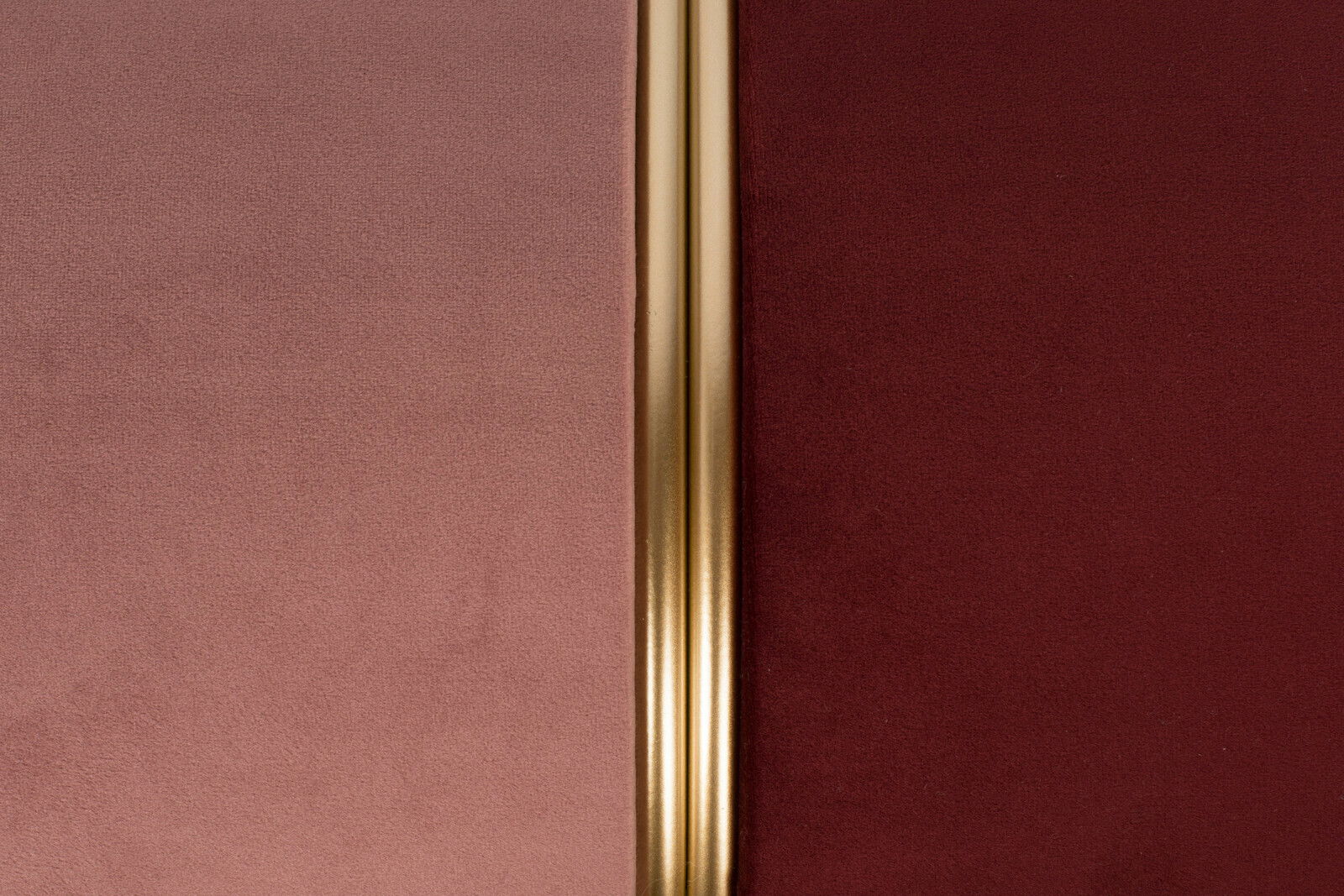 Nahaufnahme eines Hockers mit zweifarbiger Polsterung in Rosa und Rot, getrennt durch einen goldenen Streifen in der Mitte.