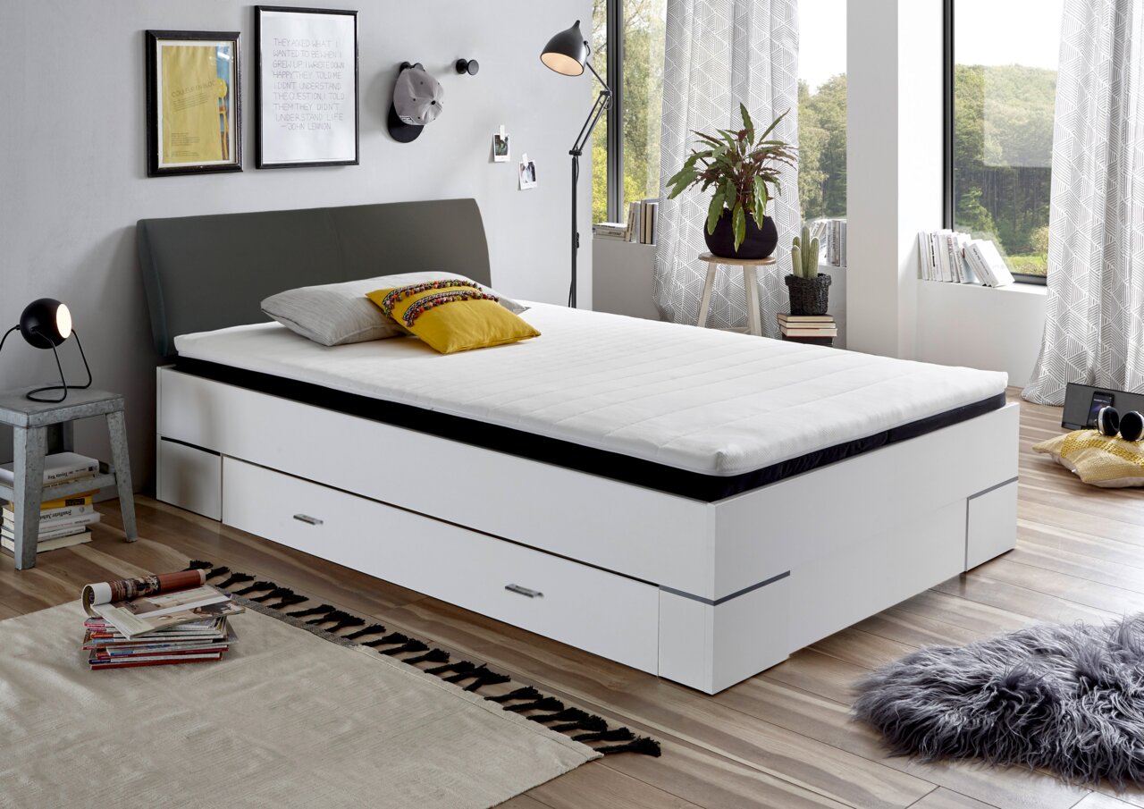 Modernes Bettgestell mit Stauraum, seitliche Perspektive, in einem stilvoll eingerichteten Schlafzimmer mit großen Fenstern.