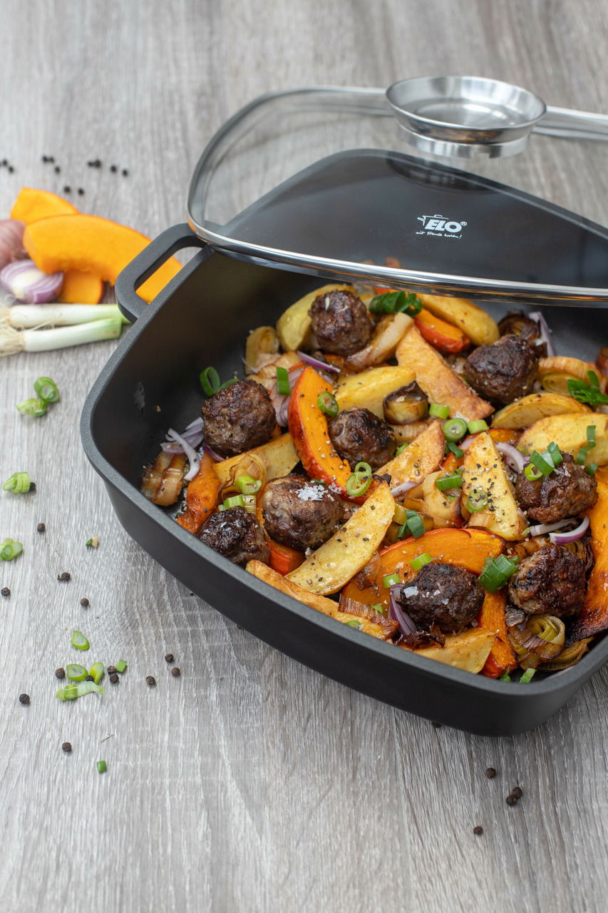 Servierpfanne Alucast mit Deckel, gefüllt mit gebratenem Gemüse und Fleischbällchen, aus der Vogelperspektive fotografiert.