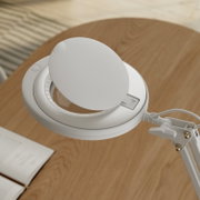 Weiße LED-Schreibtischlampe mit rundem Lampenkopf und klemmbarer Halterung auf Holztisch, Ansicht schräg von oben