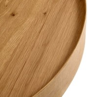 Close-up van een ronde houten salontafel met zichtbare nerf, gezien van bovenaf.