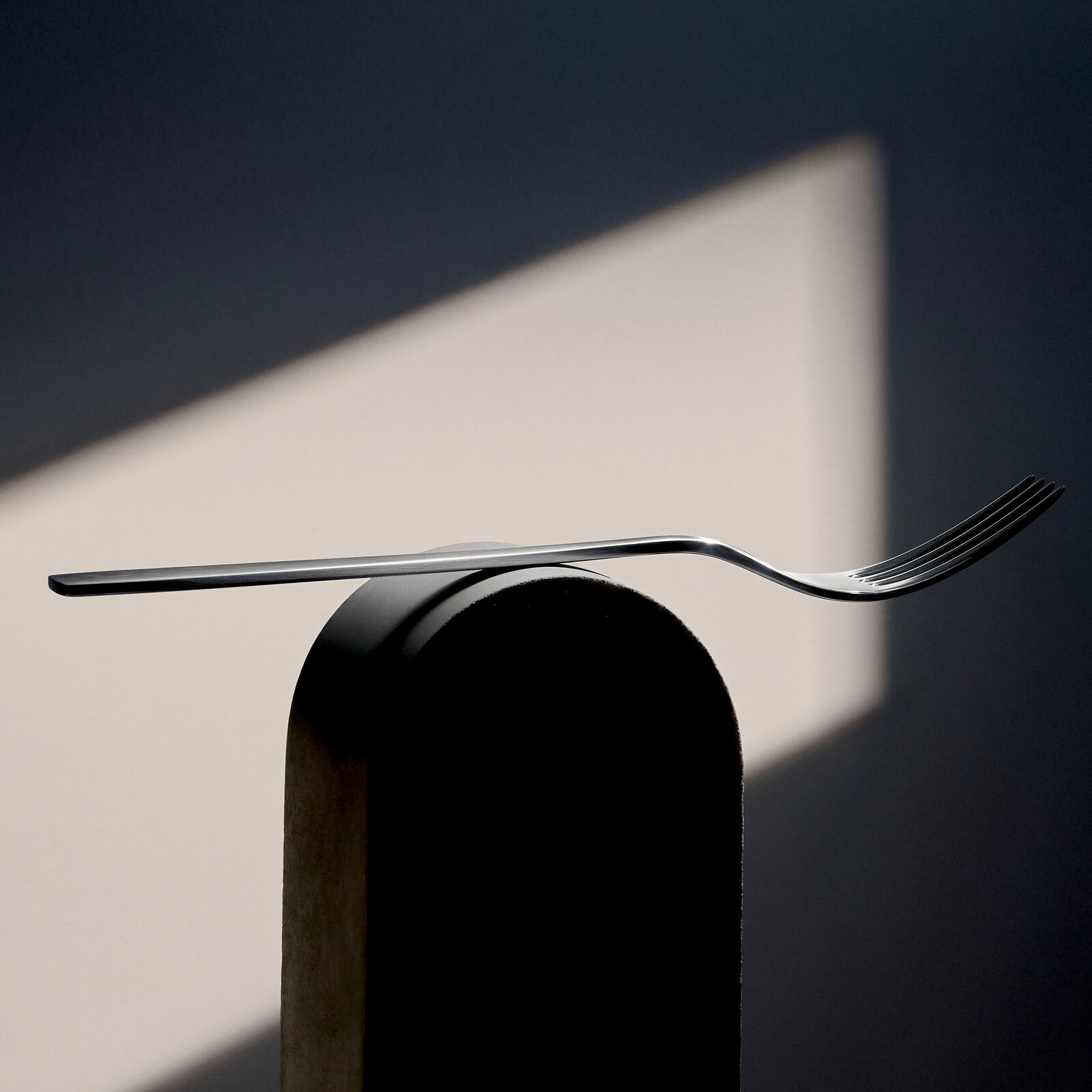 Elegante Gabel aus Edelstahl, seitlich auf einem runden Objekt balancierend, mit modernem Design und schlichter Ästhetik.
