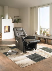 Schwarzer Fernsehsessel in einem modernen Wohnzimmer mit Kamin, aus seitlicher Perspektive.