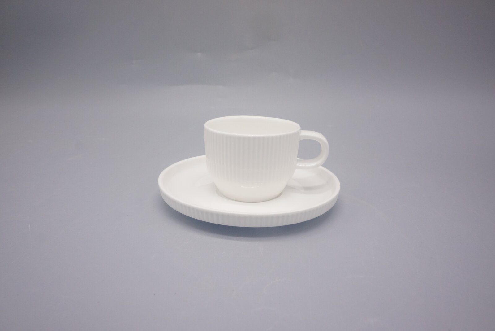 Weiße Espressotasse mit Untertasse aus Porzellan, seitliche Perspektive