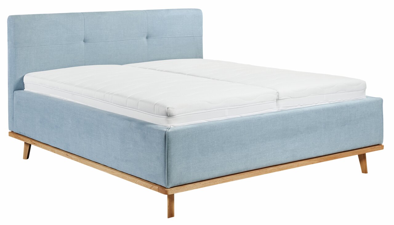 Stoffen bed met lichtblauwe bekleding en houten poten, zijaanzicht