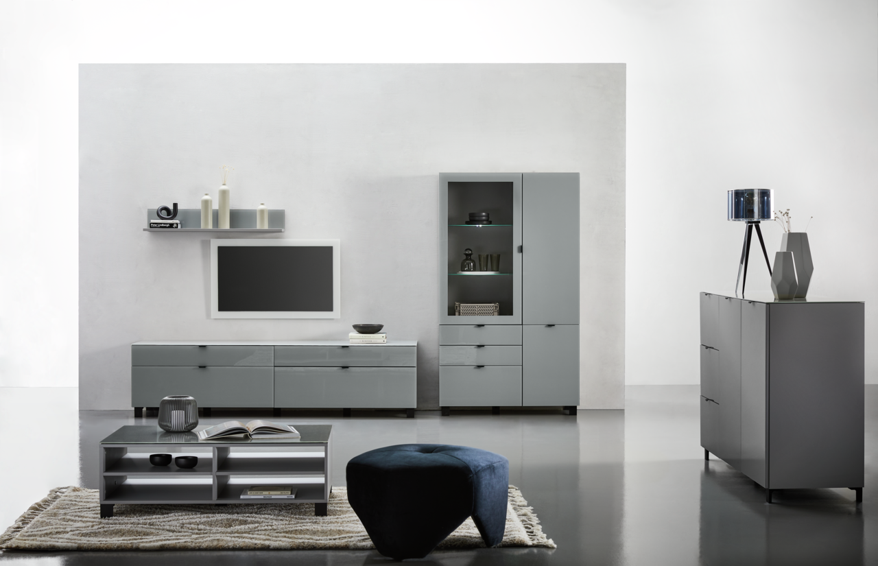Moderne Wohnzimmermöbel in grauem Design, bestehend aus einem TV-Lowboard, einer Vitrine, einem Couchtisch und einem Sideboard, aus frontaler Perspektive.