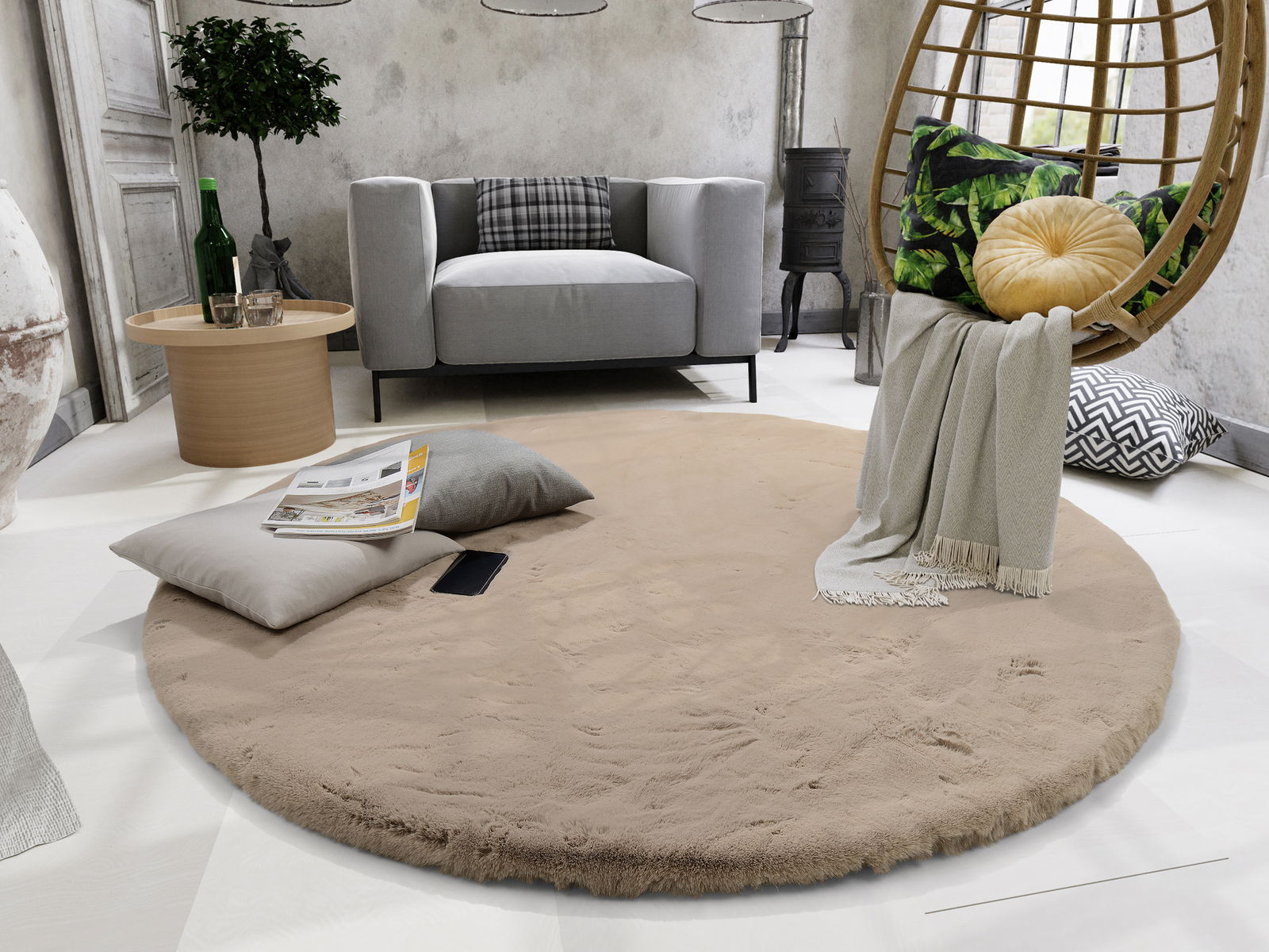 Runder, beiger Fellteppich in einem modernen Wohnzimmer, umgeben von einem grauen Sofa, einem Holztisch und einem hängenden Stuhl. Perspektive von oben.