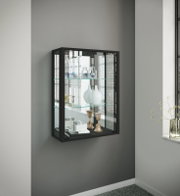 Schwarze, wandmontierte Glasvitrine mit Metallrahmen und Glaseinlegeböden, dekoriert mit Vasen und Accessoires; Perspektive: leicht schräg von vorn links.
