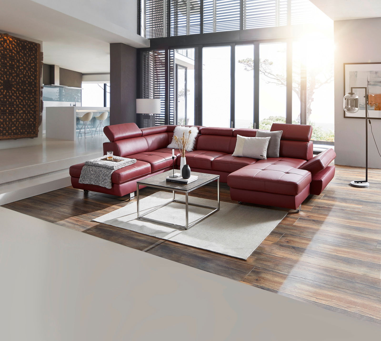 Stylife Wohnlandschaft TORINO Moderne Polsterrundecke TORINO in rotem Leder mit Bettfunktion, in einem stilvollen Wohnzimmer mit großen Fenstern und Holzboden, aus einer leicht erhöhten Perspektive fotografiert.