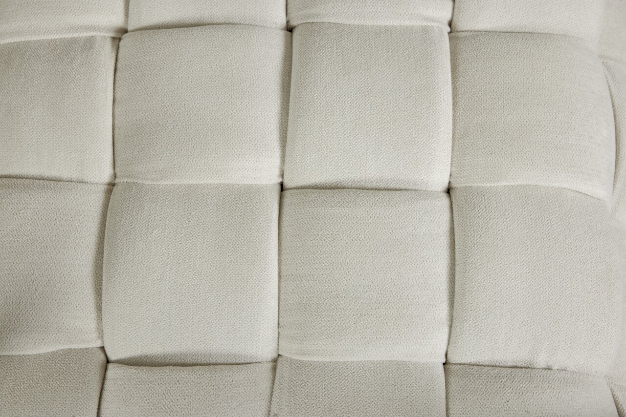 Close-up van een gestoffeerde kruk met een vierkant patroon in een crèmekleurige textuur, gezien van bovenaf.