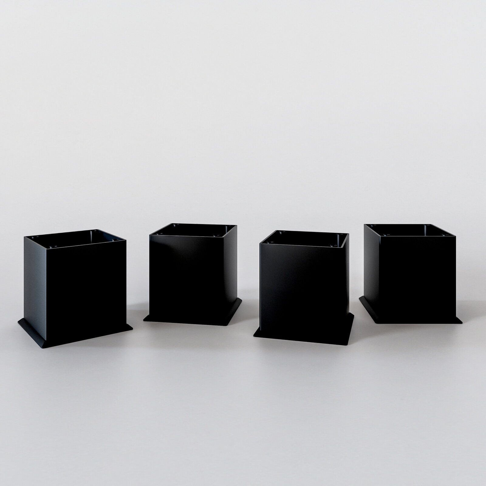 Vier schwarze quadratische Metallfüße für einen Unterschrank, frontal betrachtet auf hellem Hintergrund.