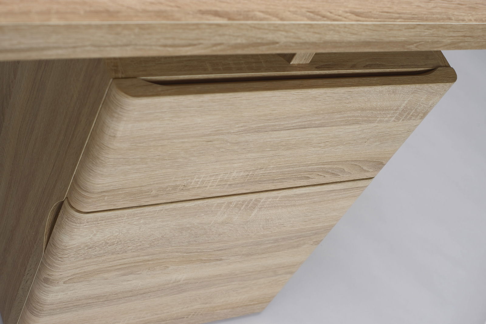 Nahaufnahme eines Schreibtisches aus hellem Holz mit Schubladen, seitliche Perspektive.