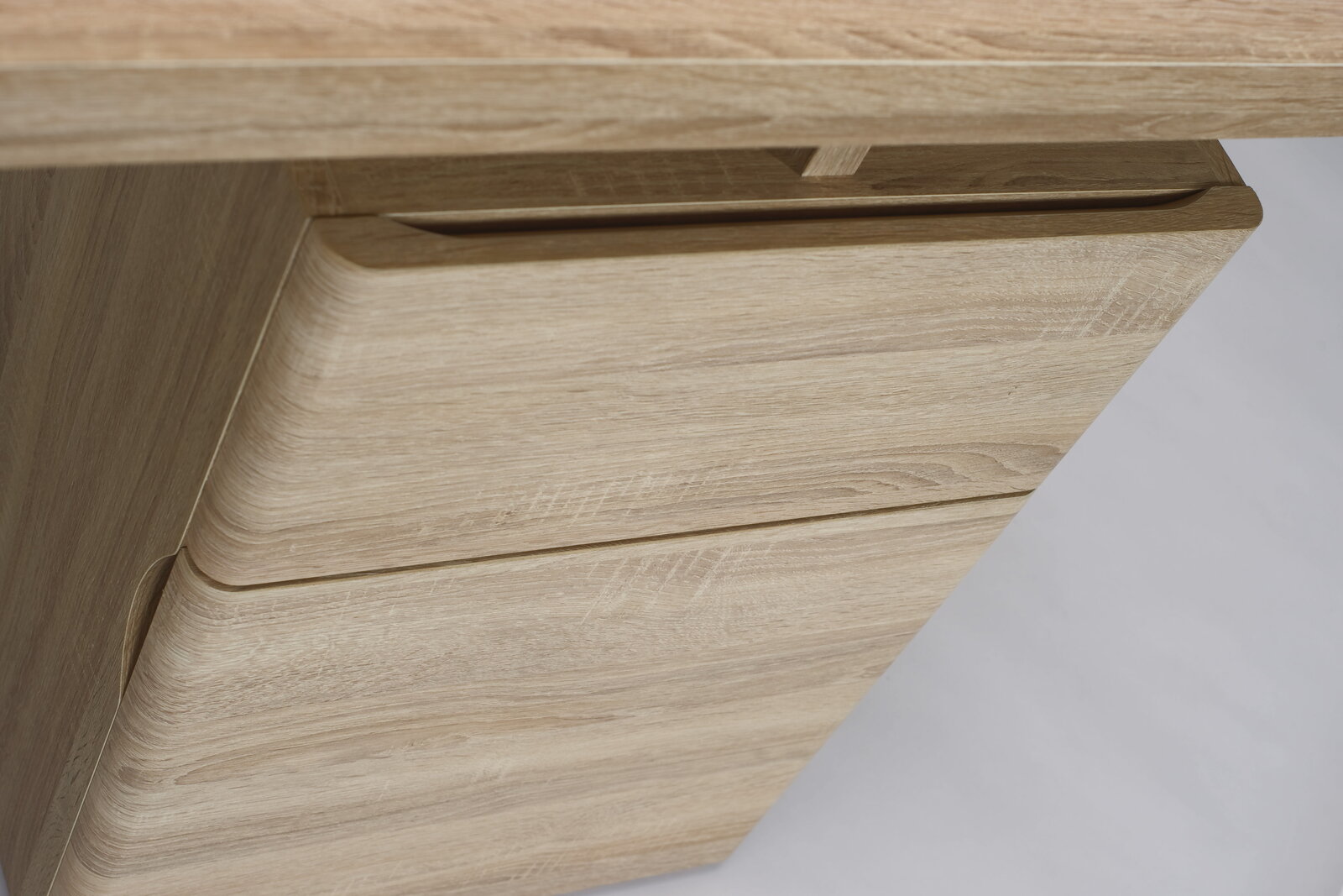 Nahaufnahme eines Schreibtisches aus hellem Holz mit Schubladen, seitliche Perspektive.