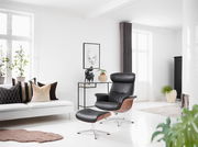 Moderner Relaxsessel mit schwarzem Lederbezug und Holzdetails, seitliche Perspektive in einem hellen Wohnzimmer.