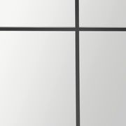 Nahaufnahme eines großen Spiegels mit schwarzem Gitterrahmen, perspektivisch von vorne betrachtet.