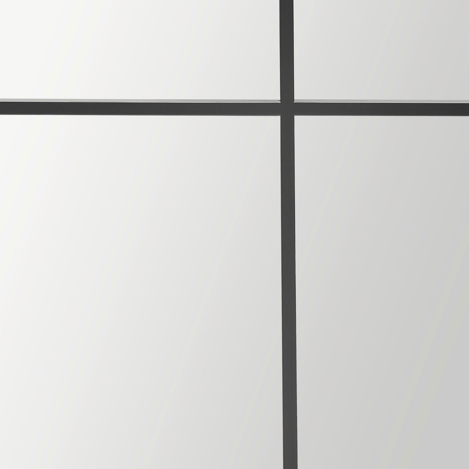 Nahaufnahme eines großen Spiegels mit schwarzem Gitterrahmen, perspektivisch von vorne betrachtet.