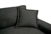 Nahaufnahme eines dunkelgrauen Big-Sofas mit geripptem Stoffbezug und passendem Kissen, seitliche Perspektive.