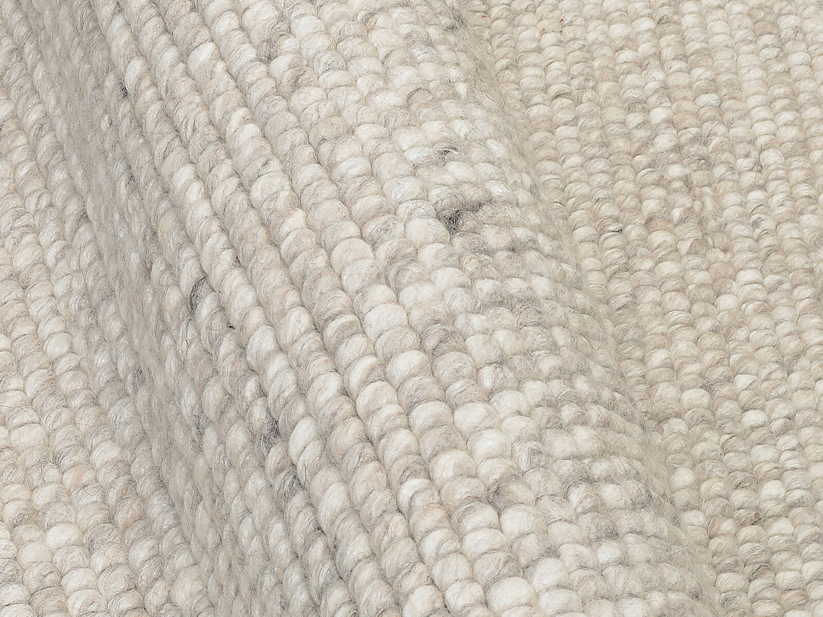 Nahaufnahme eines handgewebten Teppichs in cremefarbenen Tönen, die Textur und Webart sind deutlich sichtbar.