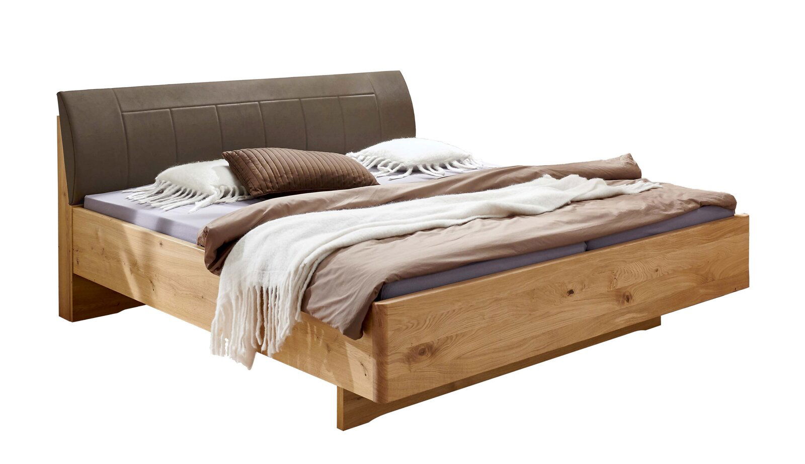 Modernes Doppelbett aus hellem Massivholz mit gepolstertem braunem Kopfteil und neutraler Bettwäsche, schräg von vorne links fotografiert